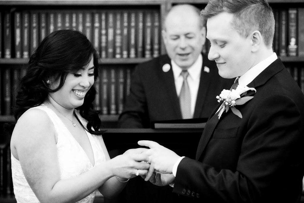 bride places ring on grooms hand during civil ceremony